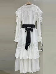 White lace dress with a black belt on a hanger against a neutral background