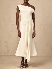 Woman wearing a white one-shoulder dress against a beige background