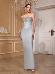 Woman wearing a strapless, beaded evening gown in an elegant room with a chandelier.