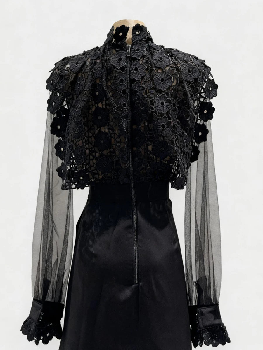 Black lace top with sheer sleeves on a mannequin against a white background