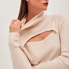 Close-up of a beige ribbed sweater with cut-out design on a plain background