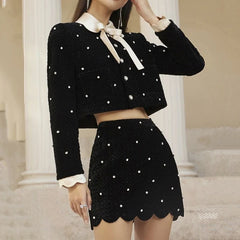 Woman wearing a black polka dot outfit with a white collar and bow tie in an indoor setting.