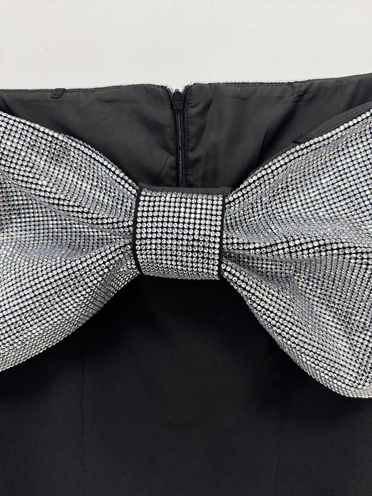 Black jacket with a large, decorative bow made of crystals on a white background