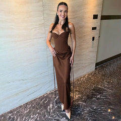 Woman in a brown dress standing against a marble wall.