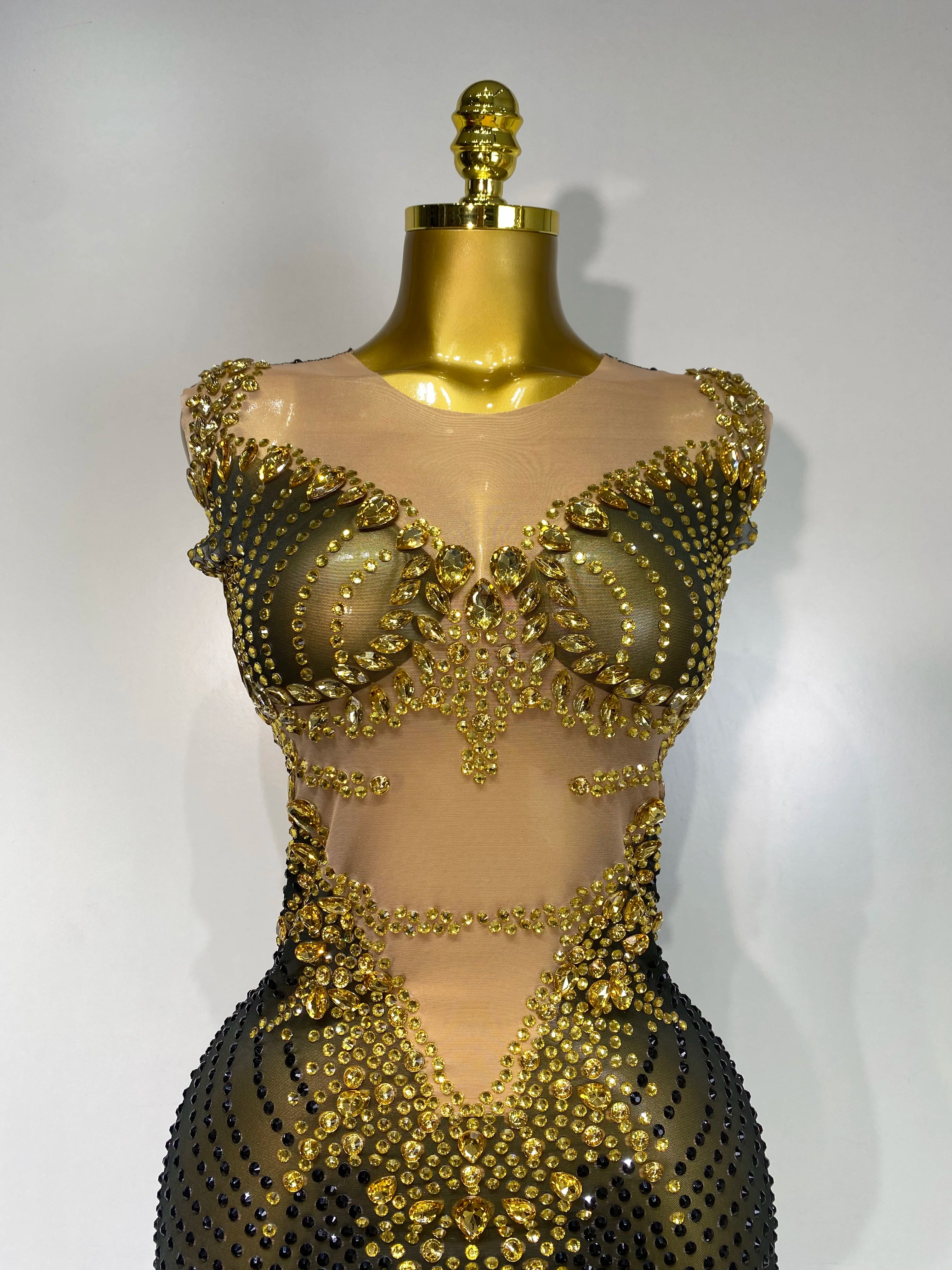 Gold beaded dress on a mannequin against a white background