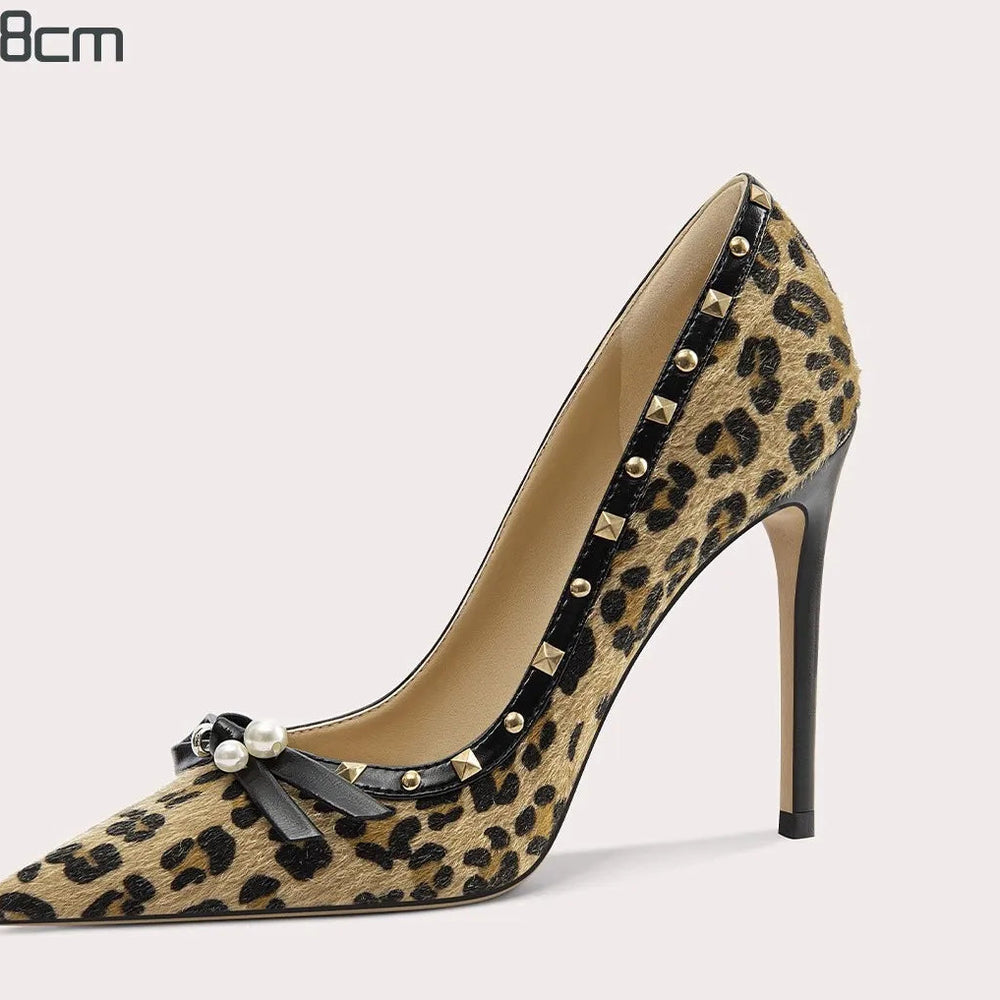 Leopard print high-heeled shoe with studded details on a light gray background