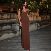 Woman in a brown evening gown standing outdoors at night.