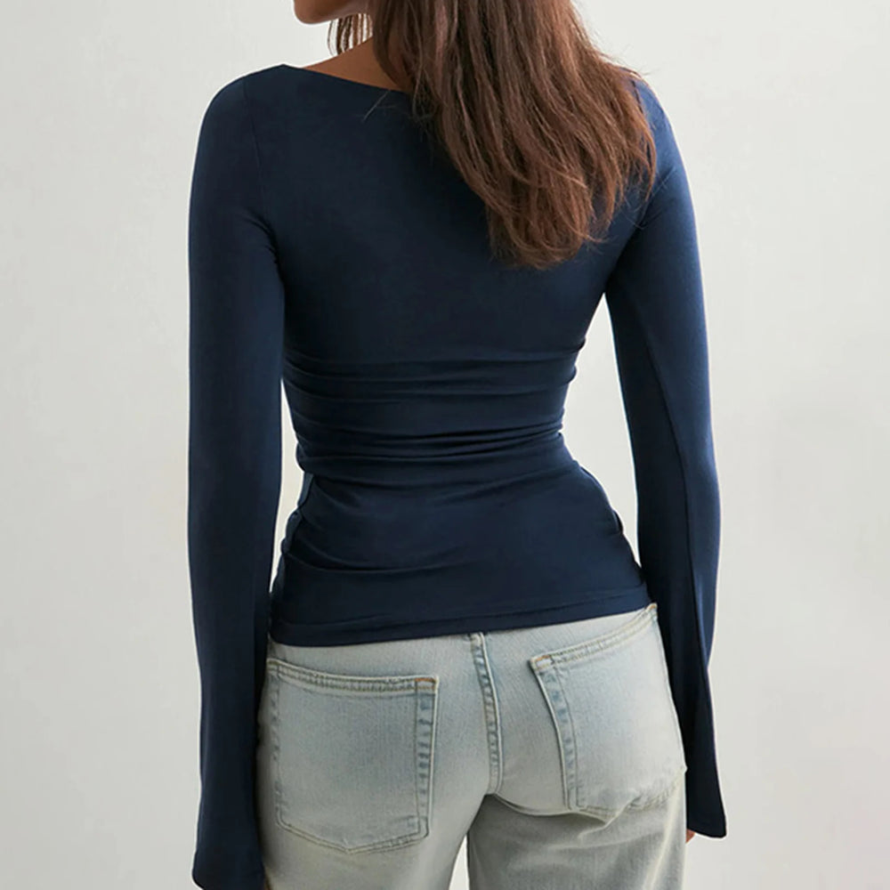 Person wearing a navy long-sleeve top and light blue jeans on a plain background
