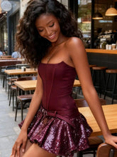 Woman in a burgundy dress with sequin skirt standing in an outdoor cafe setting