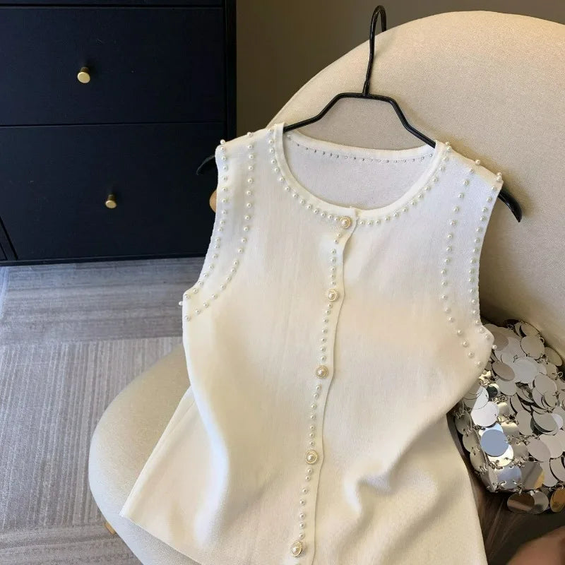 White sleeveless top with pearl details on a mannequin against a neutral background