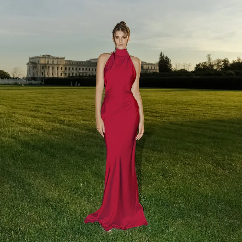 Woman in a red dress standing in a grassy field with a building in the background