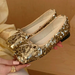 Close-up of sparkling sequin bow ballet flats held by a hand