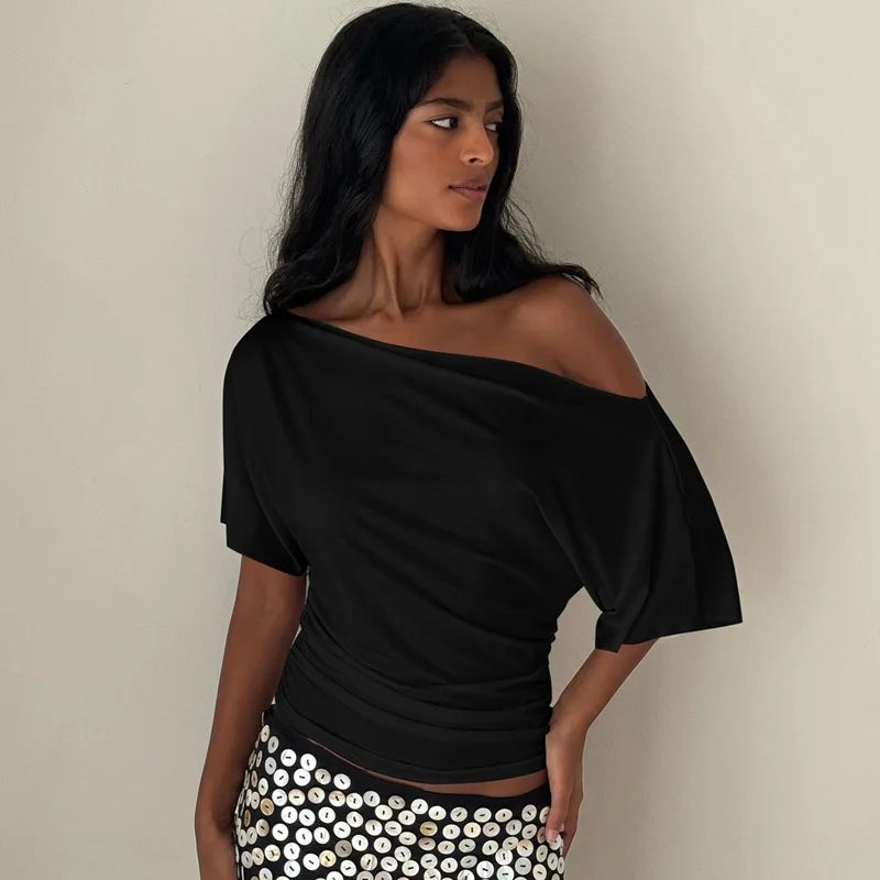 Woman wearing a black off-shoulder top with a plain background