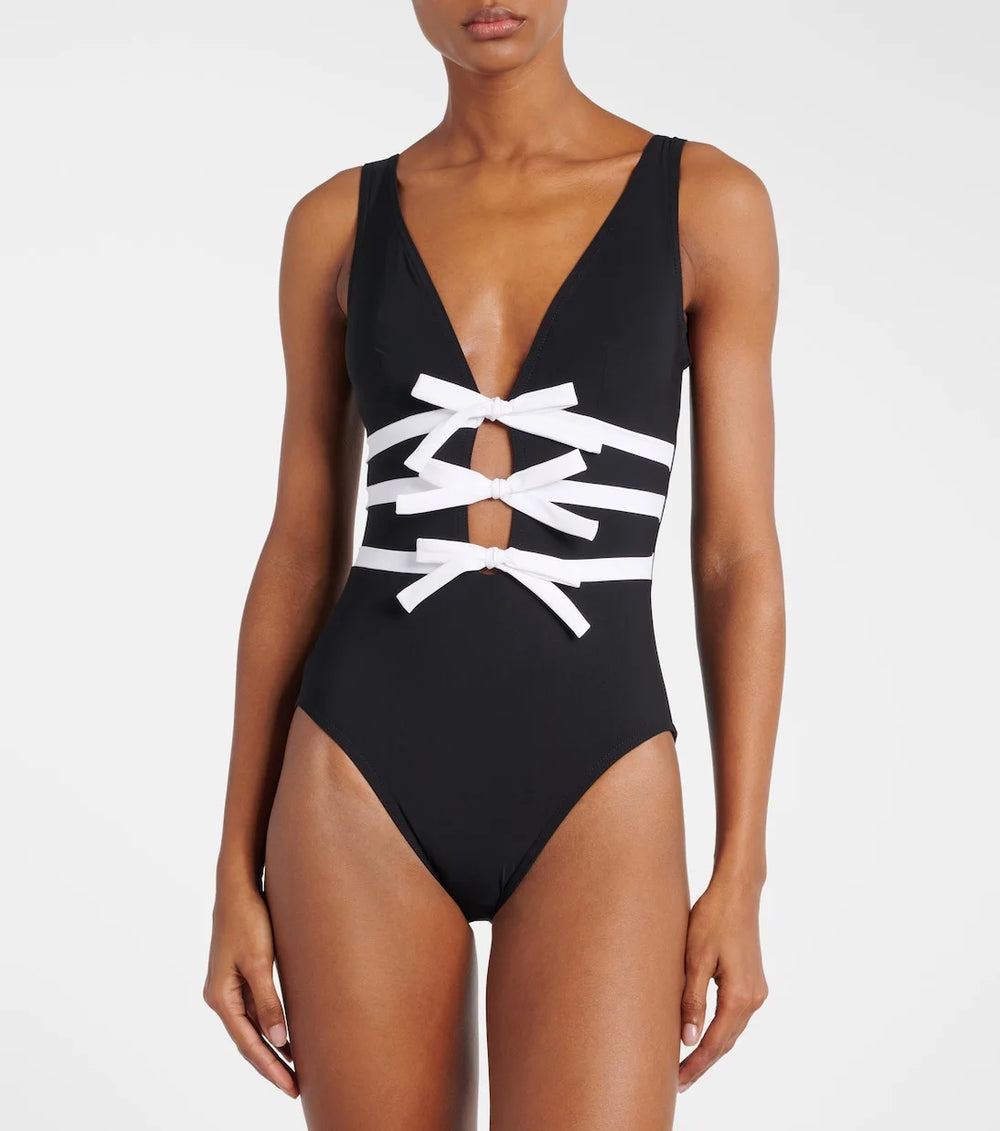 Close-up of a monochrome one-piece swimsuit featuring intricate white bow lacing detail on the torso.