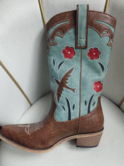 Brown and turquoise cowboy boot with floral design on a light gray background