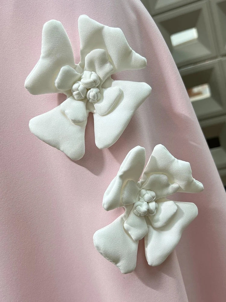 White floral earrings on a pink fabric background