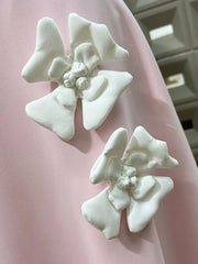 White floral earrings on a pink fabric background