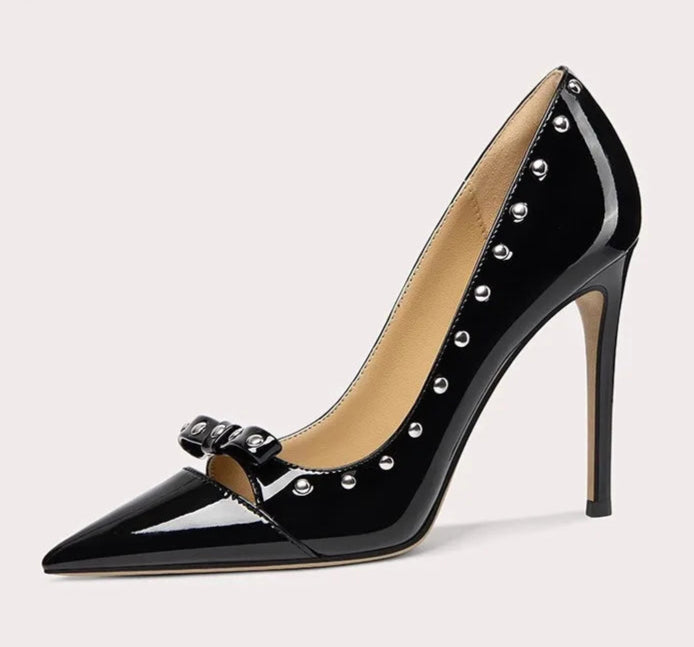 Black high-heeled shoe with studded details on a light gray background