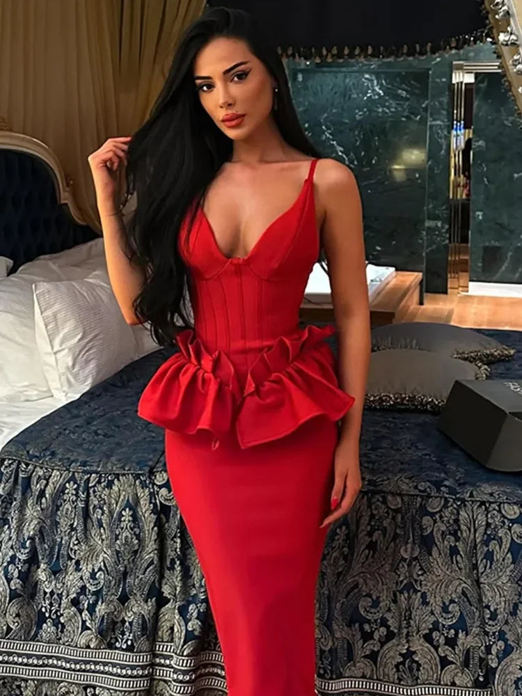 Woman in a red dress standing in an elegant room with a bed and mirror.