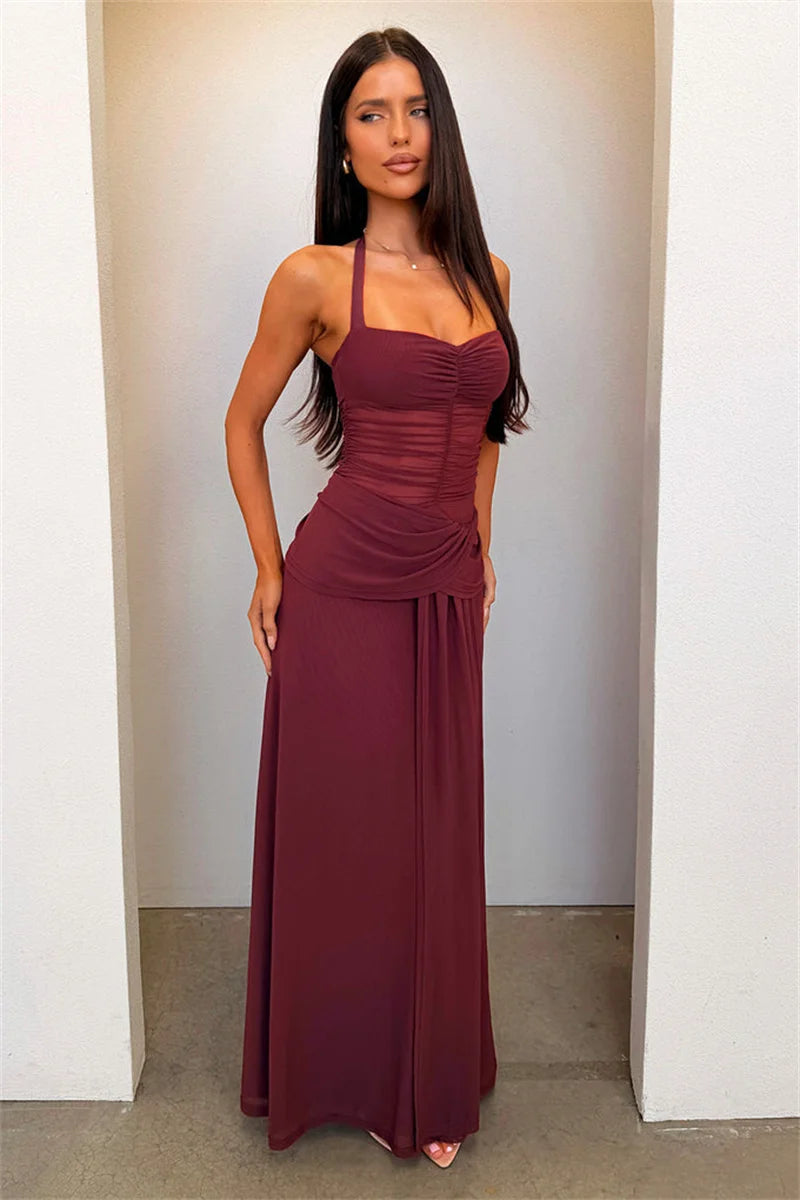 Woman wearing a burgundy dress standing against a plain wall.