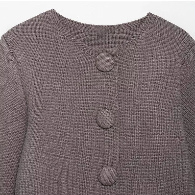 Close-up of a gray textured cardigan with button details on a light gray background