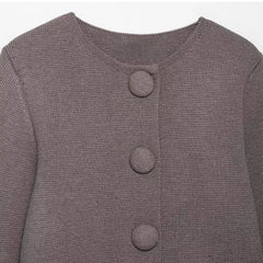 Close-up of a gray textured cardigan with button details on a light gray background