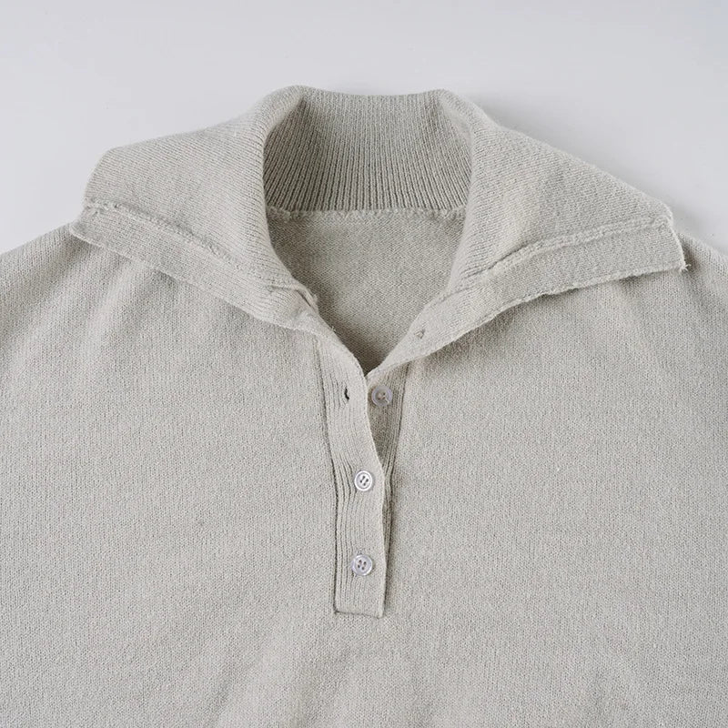 Close-up of a light gray sweater with a collar and buttons on a white background