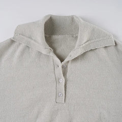Close-up of a light gray sweater with a collar and buttons on a white background