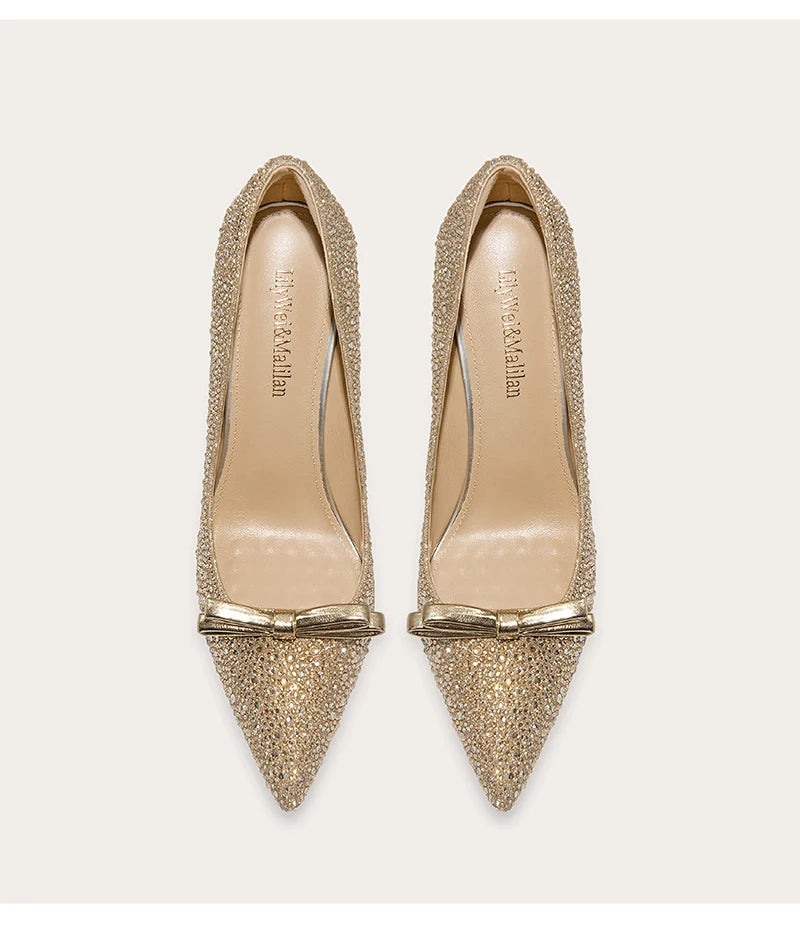 Gold glittery pointed-toe shoes with bow detail on a white background