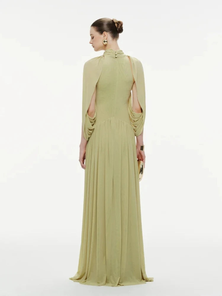 Woman wearing a long green dress with cut-out shoulders on a white background