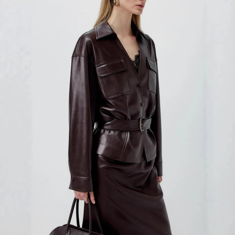 Person wearing a dark brown leather jacket and skirt set on a light gray background