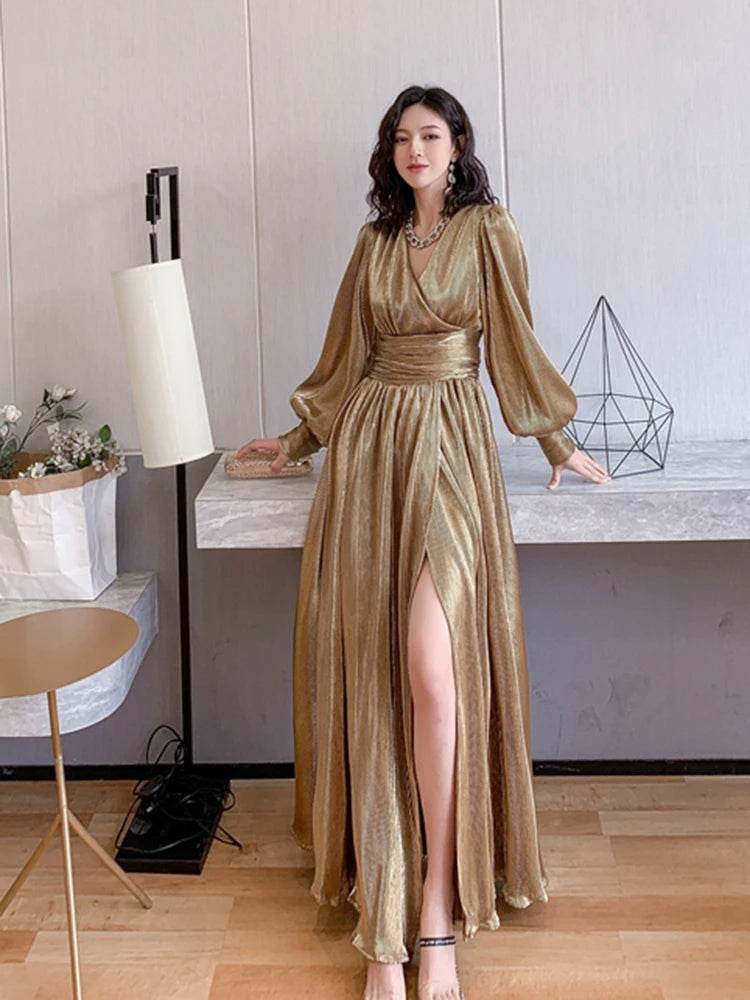 Woman in a gold dress standing indoors with a neutral background