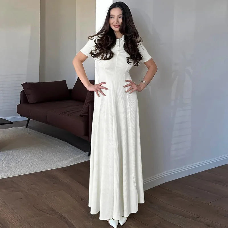 Woman in a long white dress standing in a modern living room.