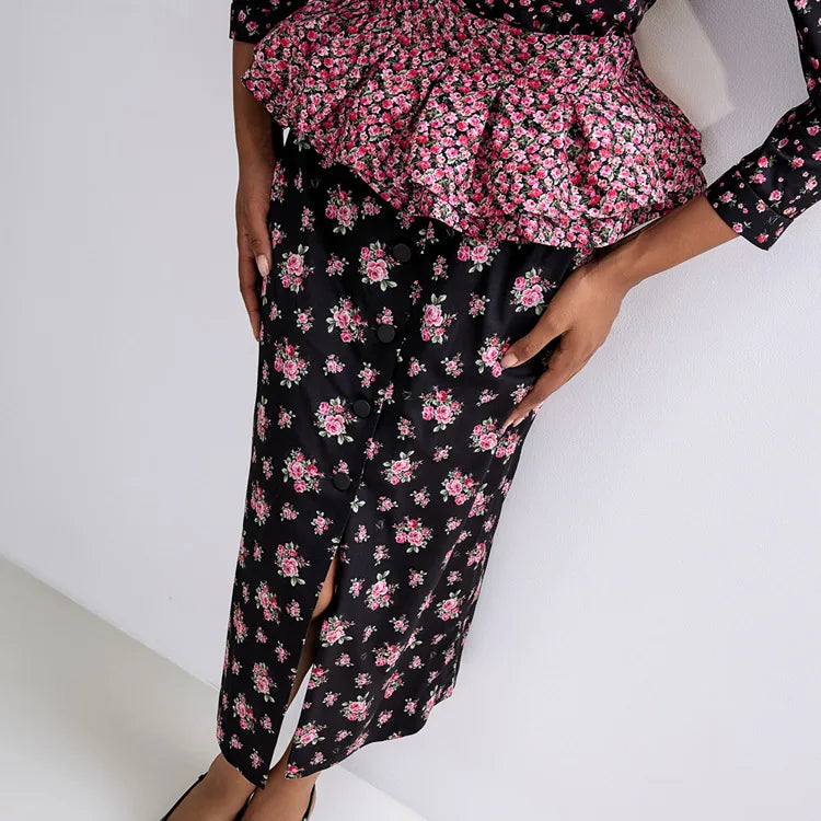 Person wearing a black floral outfit with pink flowers on a white background
