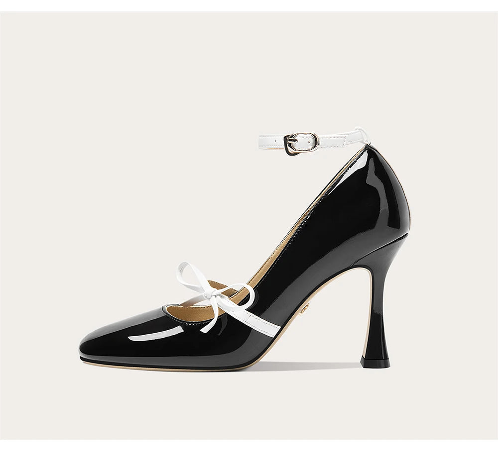 Black patent leather shoe with white bow on a light gray background