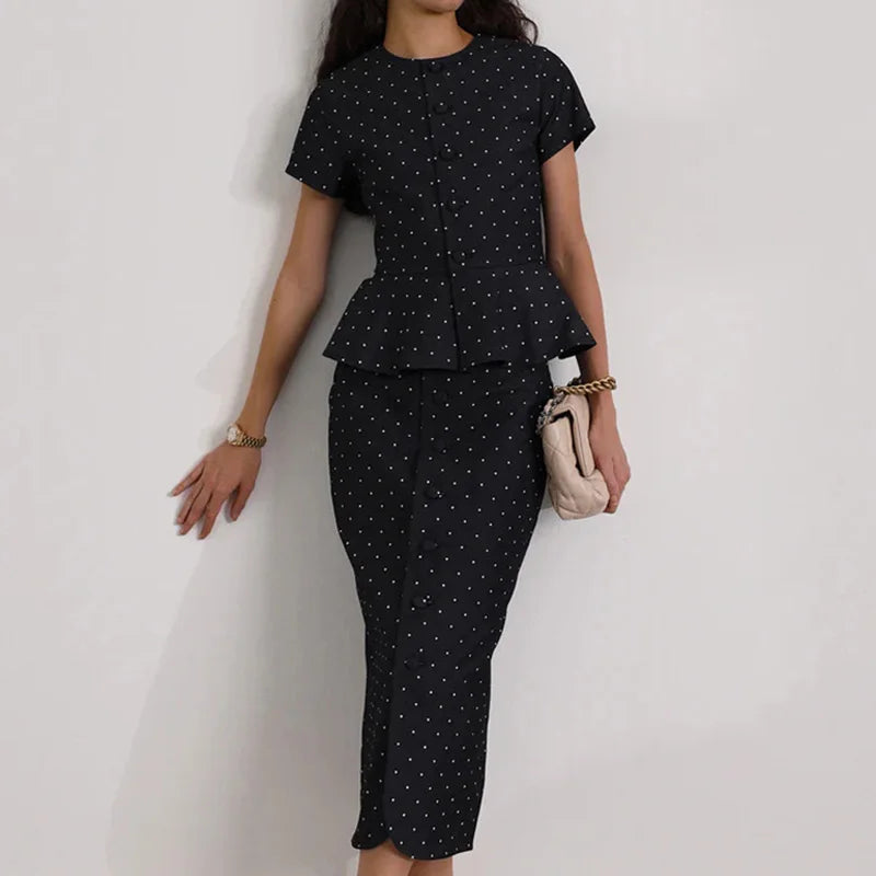 Woman wearing a black polka dot outfit with a peplum top and high-waisted pants