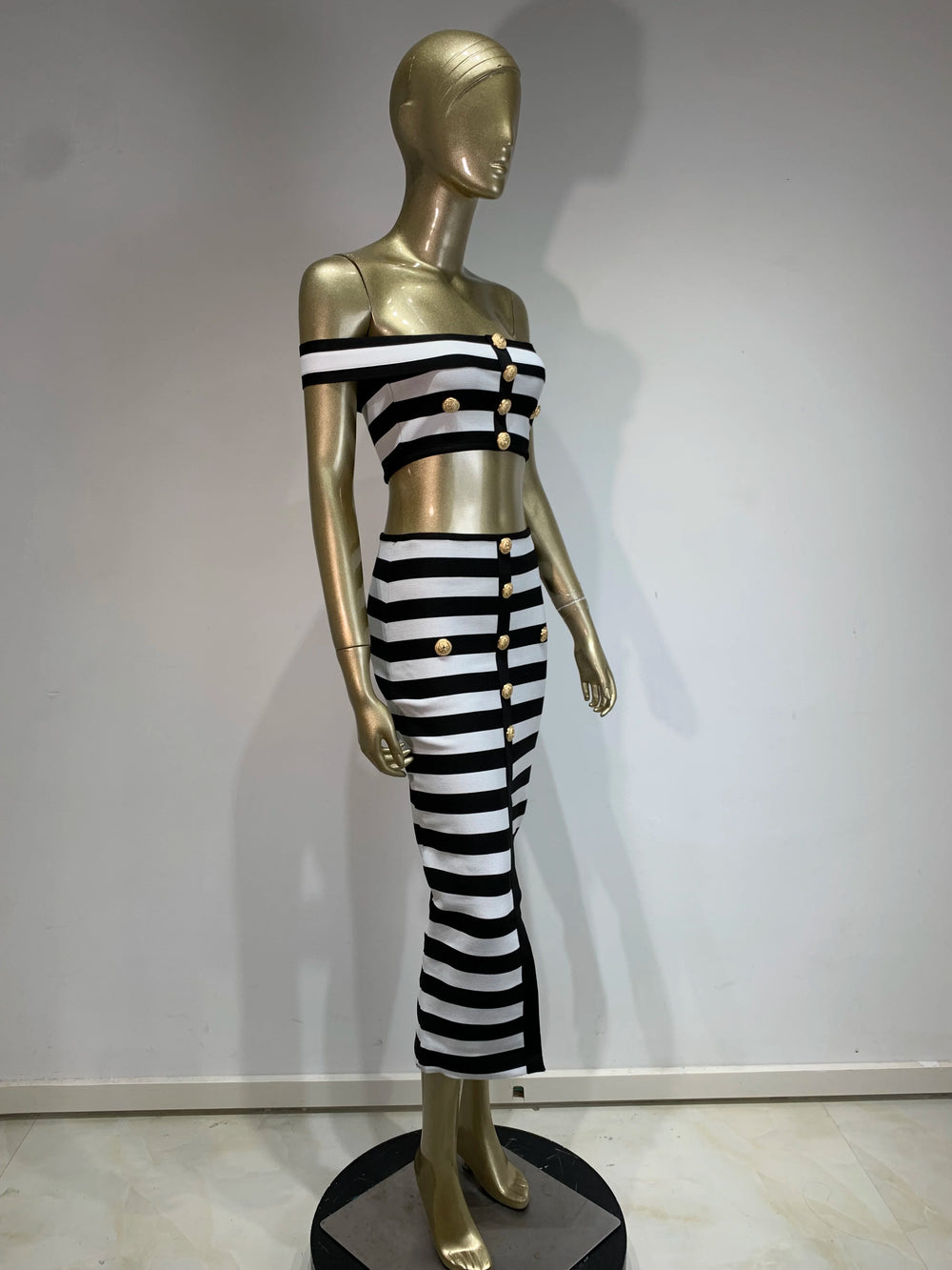 Mannequin wearing a black and white striped outfit with gold buttons against a plain background