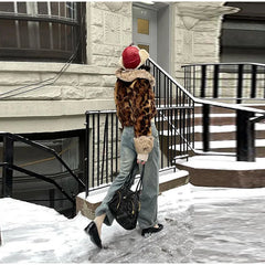 Person walking in the snow wearing a leopard print coat and red beanie with a teddy bear design.