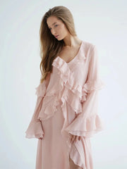 Woman wearing a light pink ruffled dress against a white background