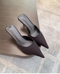 Pair of brown high-heeled shoes on a wooden surface.
