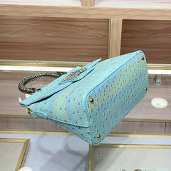 Side view of the blue ostrich print textured handbag, highlighting its structured shape.
