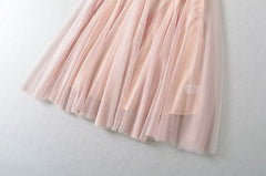 Close-up of the flowing tiered tulle hem of a pink formal gown.