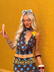 Woman in a polka dot outfit with sunglasses on her head, against a yellow background