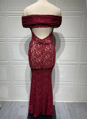 Red lace dress on a mannequin against a white paneled wall.