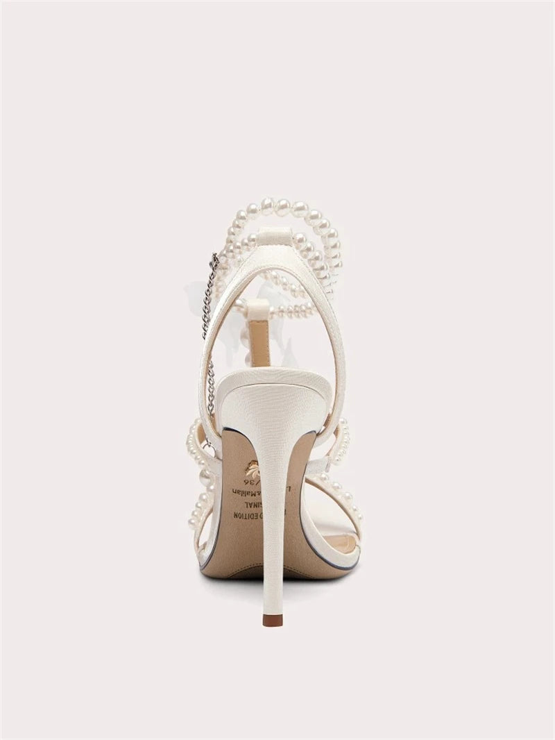 White high-heeled shoe with pearl embellishments on a light gray background