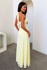 Woman in a long, light-colored dress standing in a minimalistic room.