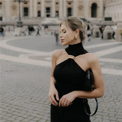 Woman in a black dress with gold accents standing in an urban setting