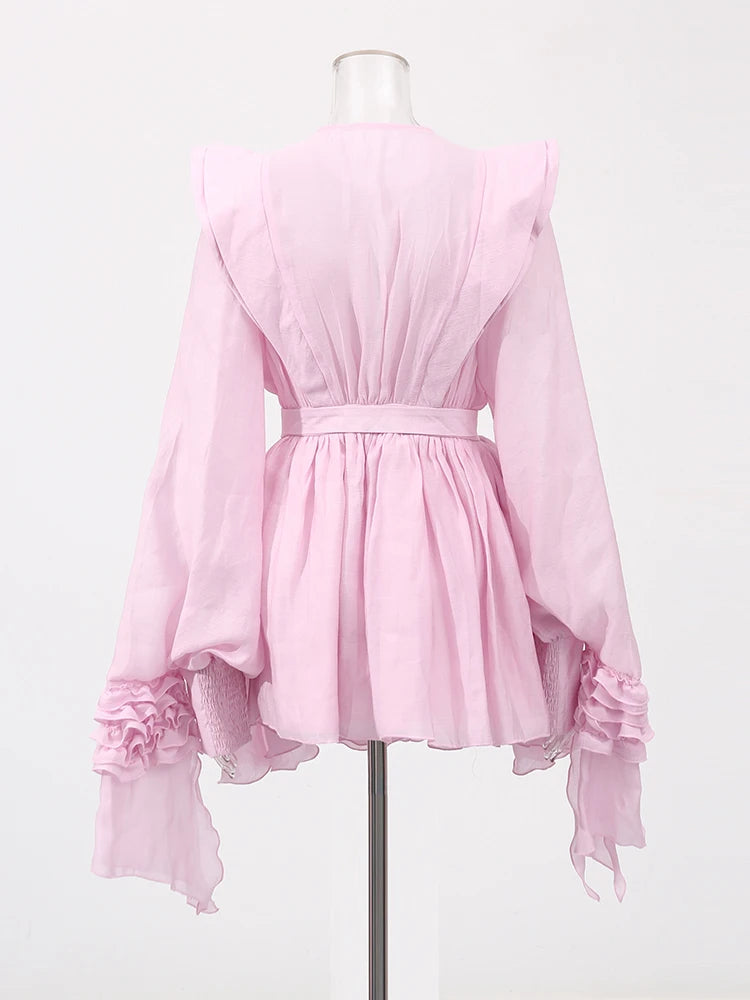 Pink blouse with ruffled sleeves on a mannequin against a white background