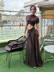 Woman in a brown dress standing on a rooftop with cityscape in the background