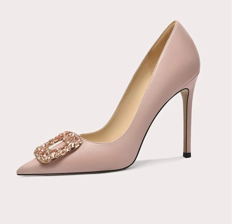 Beige high-heeled shoe with a decorative buckle on a light gray background